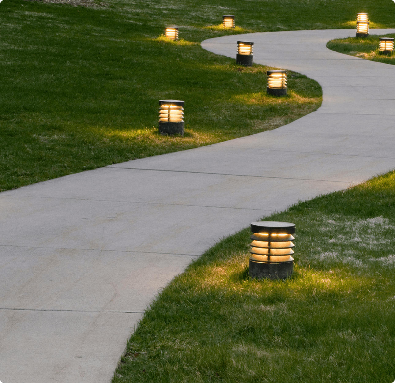 Illuminated walkway surrounded by grass