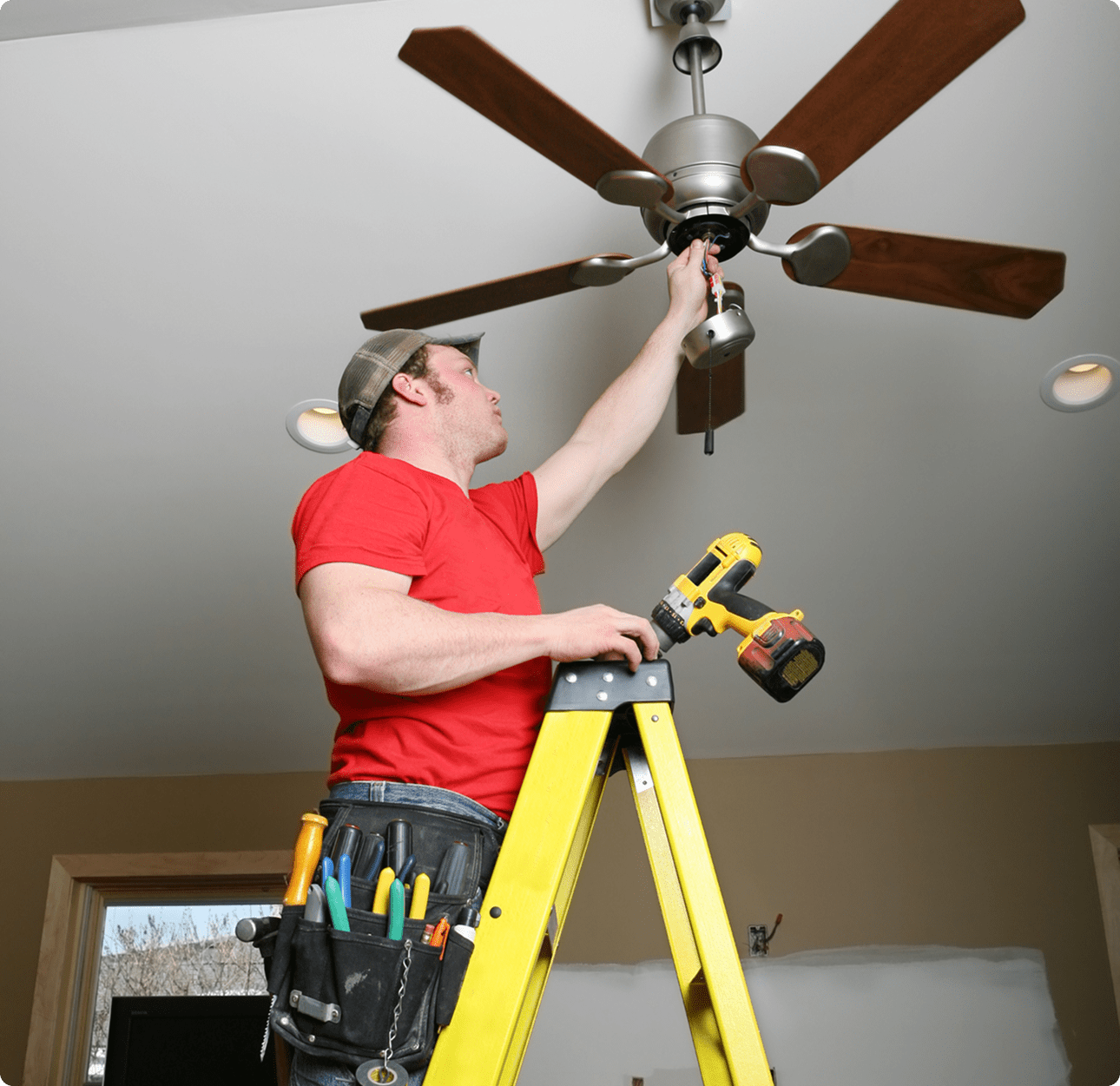 Worker installing ceiling fan indoors